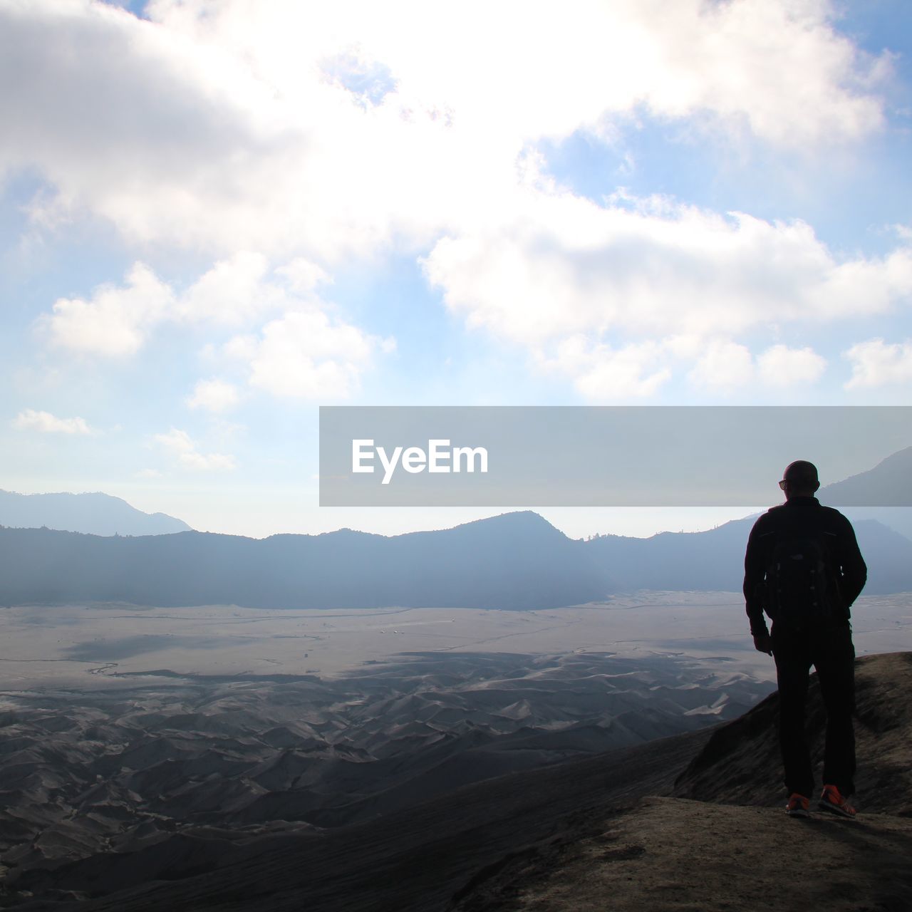 Rear view of man standing on mountain against sky