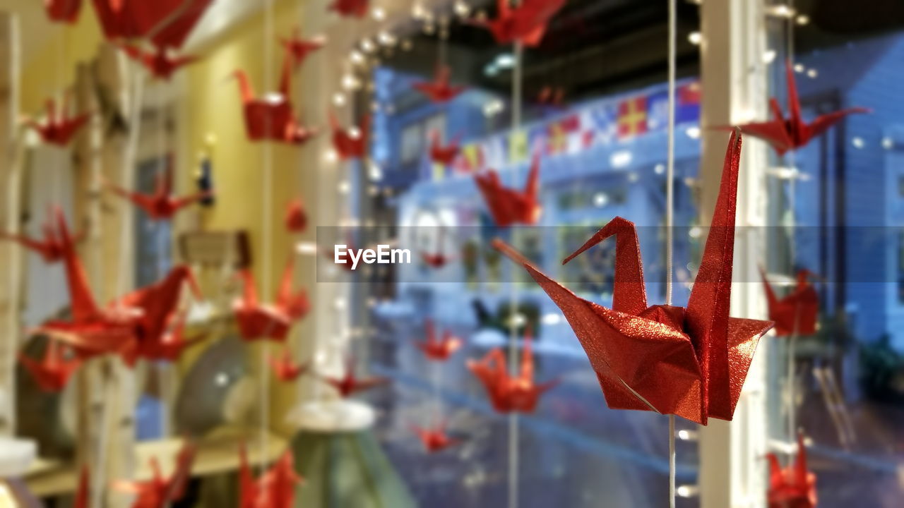 Origami paper cranes hanging against glass window