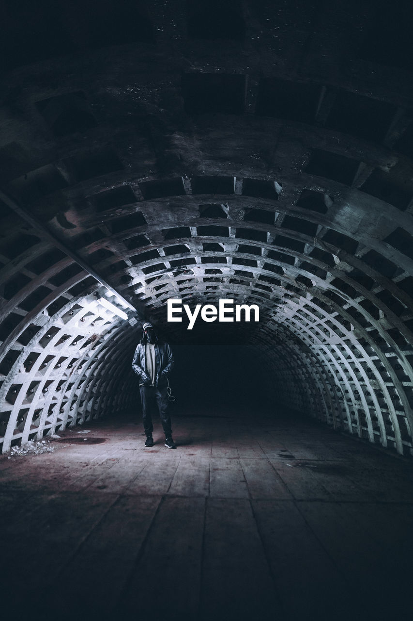 Man wearing hoodie standing in tunnel