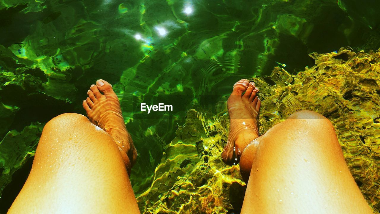 Low section of woman dipping feet in water