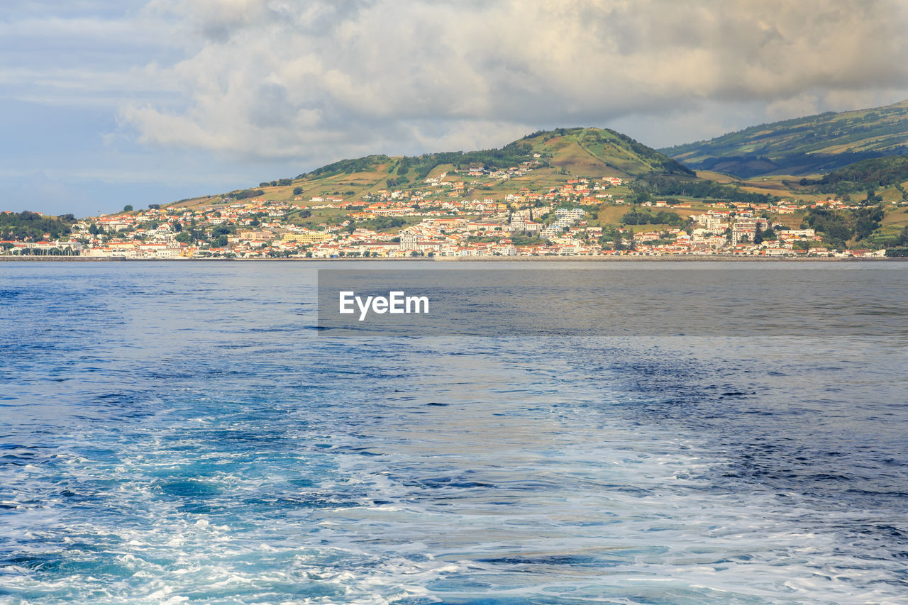 Scenic view of sea by buildings against sky