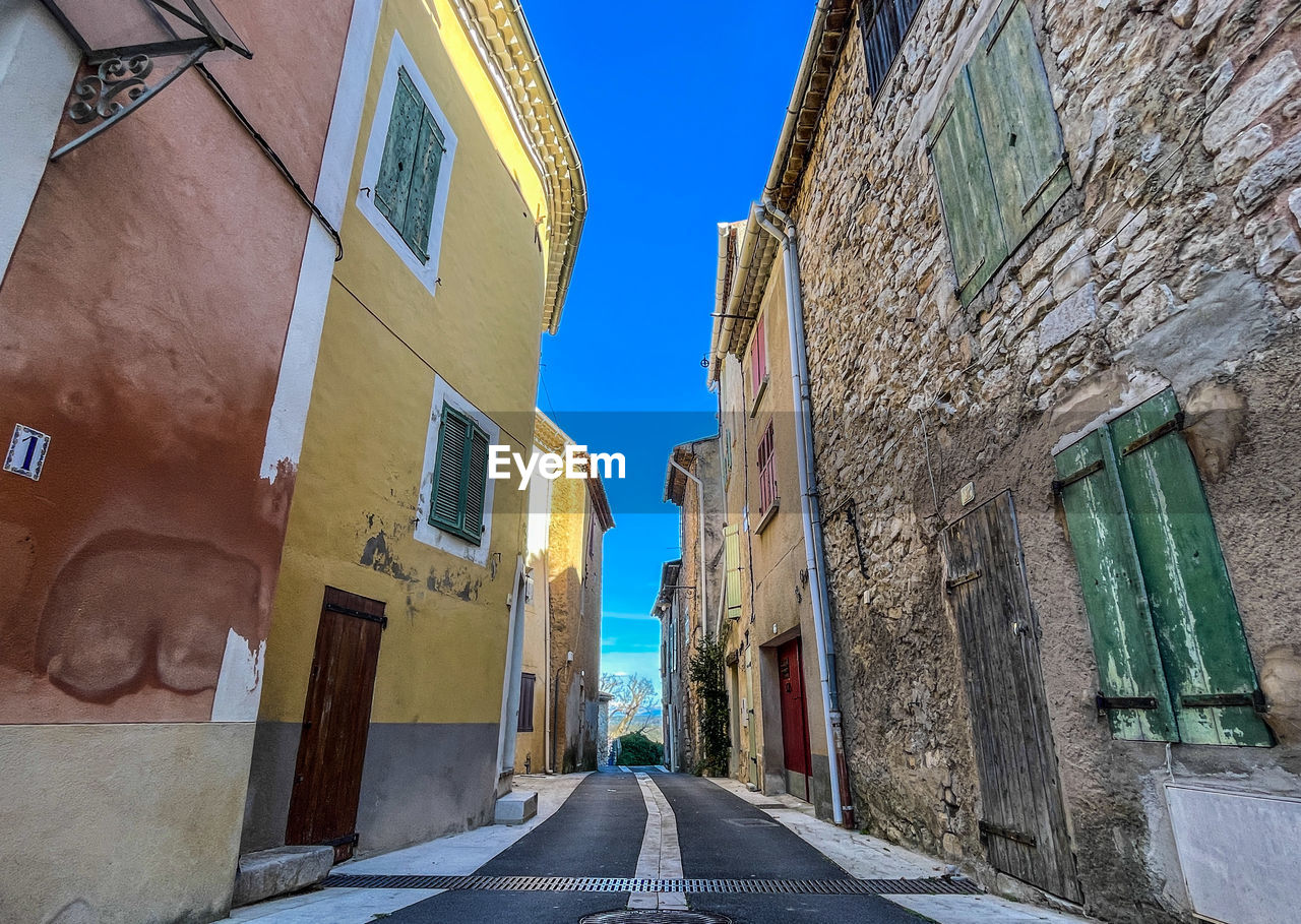 road, architecture, street, alley, building exterior, built structure, neighbourhood, town, city, infrastructure, building, urban area, lane, wall, the way forward, residential district, nature, no people, day, sky, facade, diminishing perspective, transportation, clear sky, window, house, blue, outdoors, travel destinations, old, sign, wall - building feature, sunlight