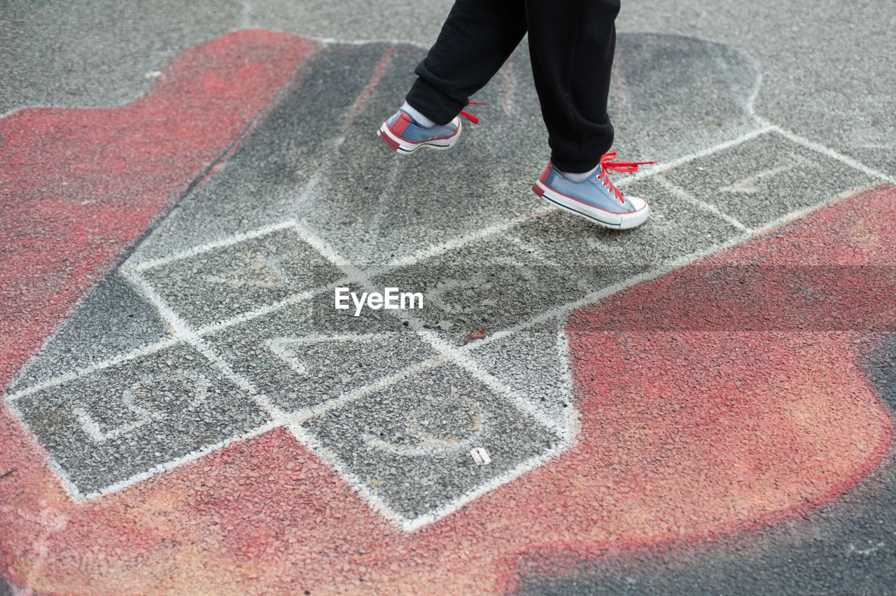 Low section of person playing hopscotch on street