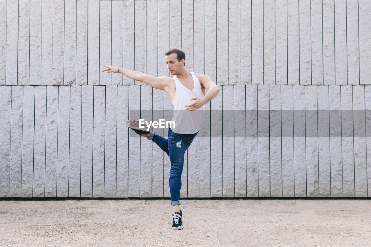 Full length of man jumping while dancing against wall