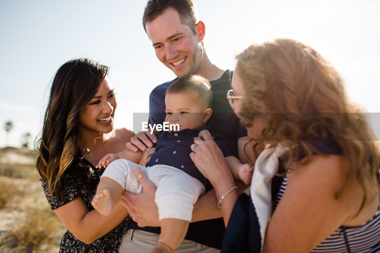 Family smiles as dad holds baby on beach