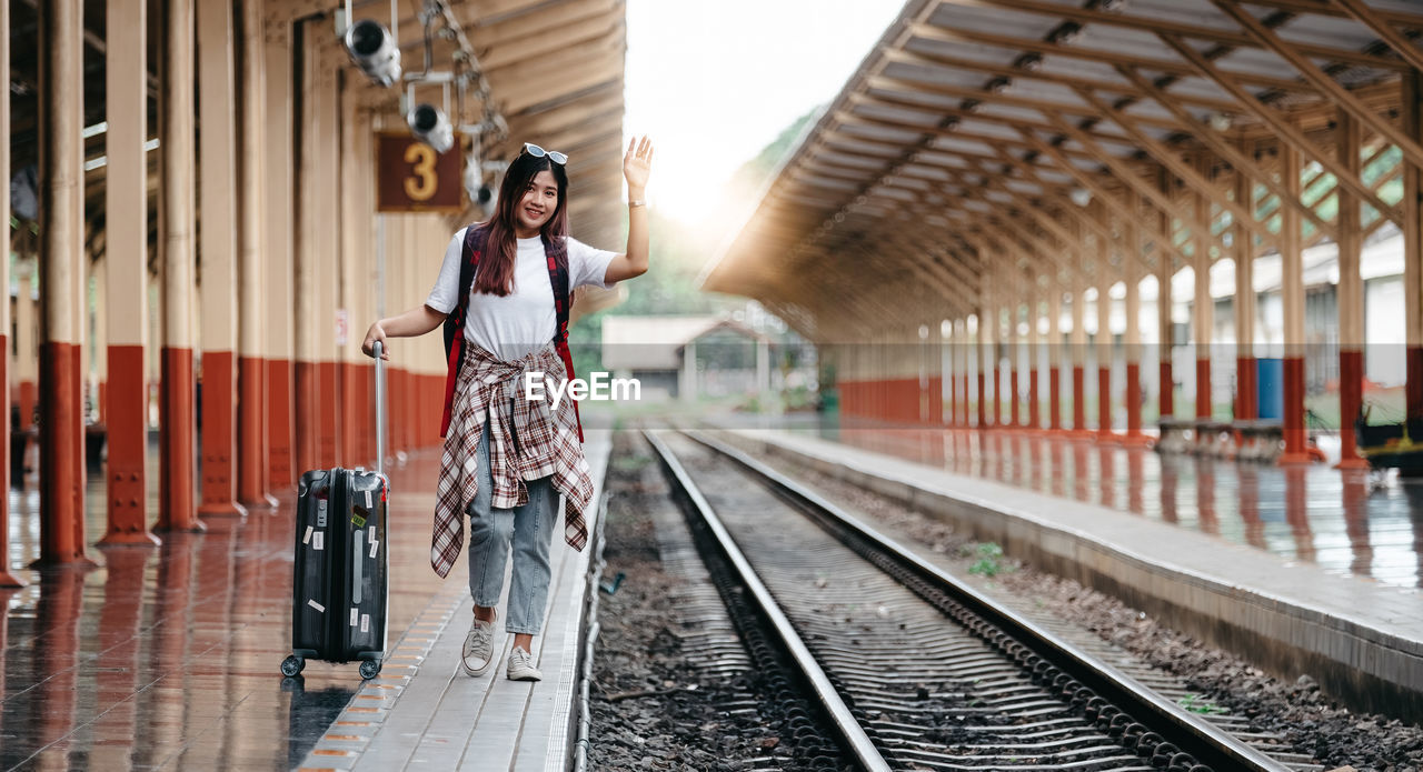 Portrait traveler asian woman walking and waits train on railway platform.