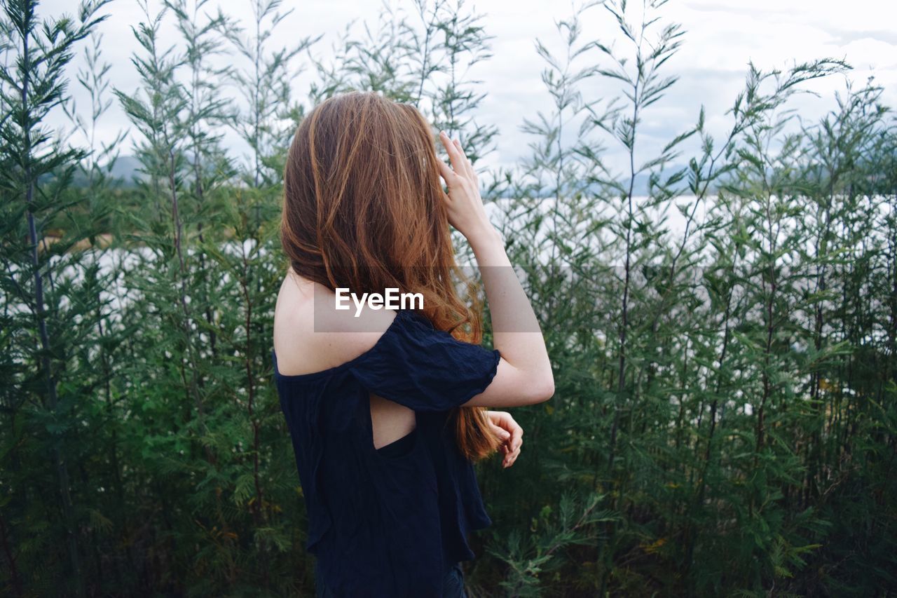 Rear view of young woman standing against plants