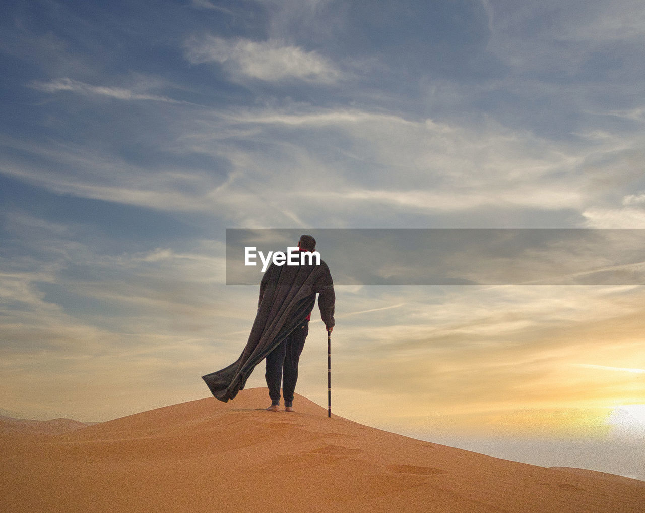 rear view of man standing on sand at desert