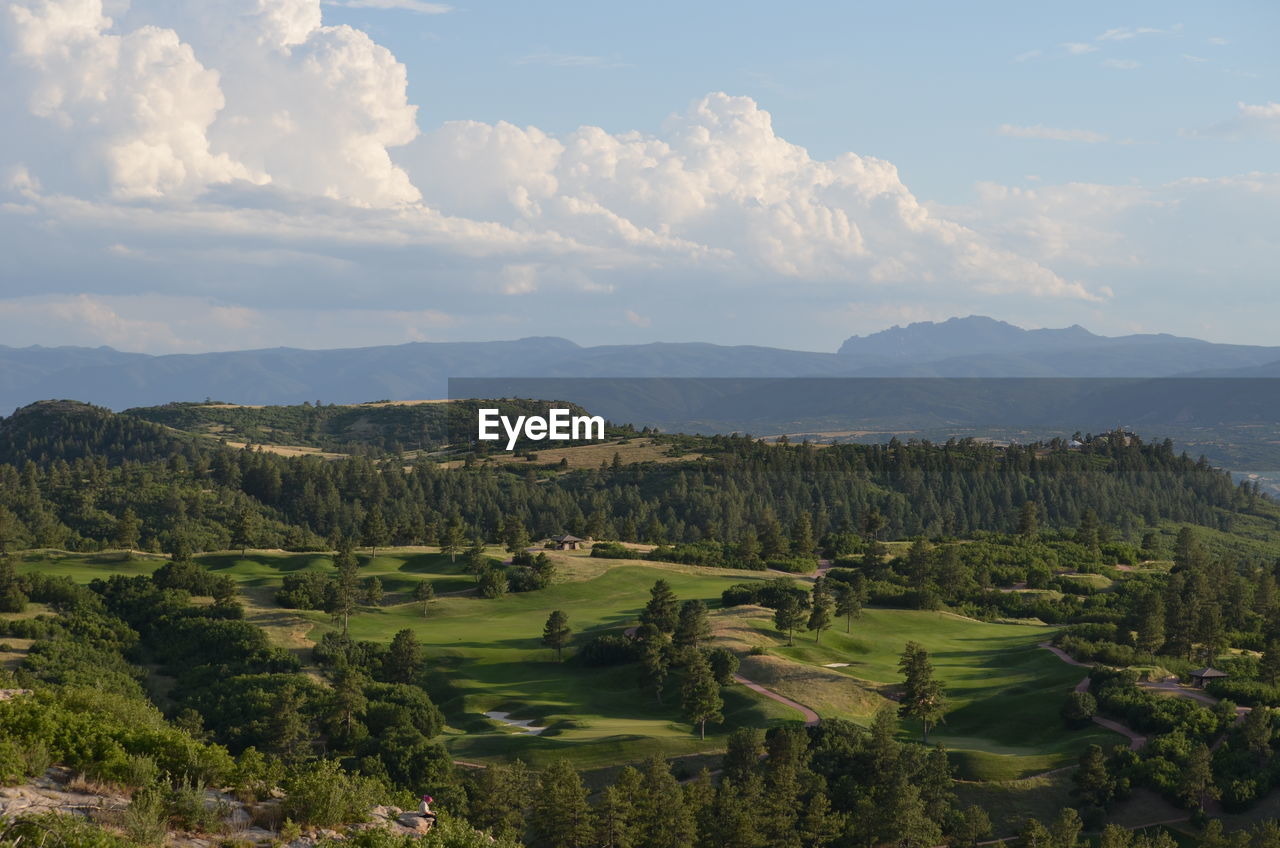 High angle view of golf course and mountains against sky