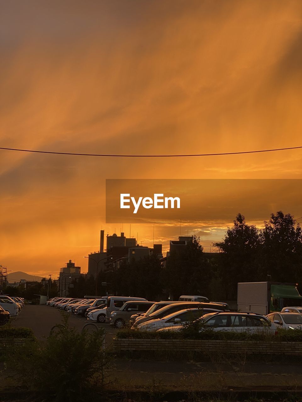 CITY STREET BY BUILDINGS AGAINST ORANGE SKY