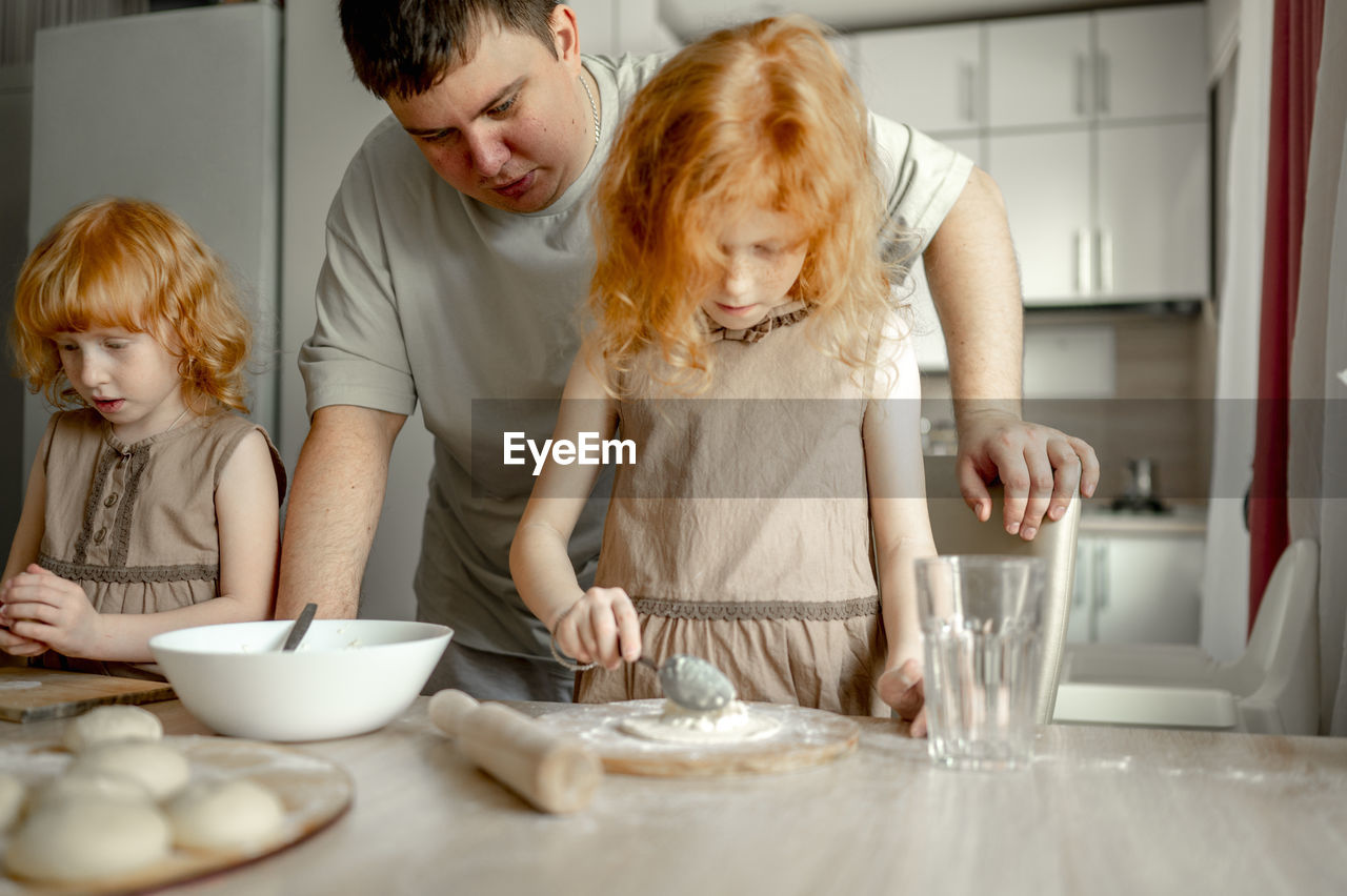 Father with daughters preparing cheesecake at home