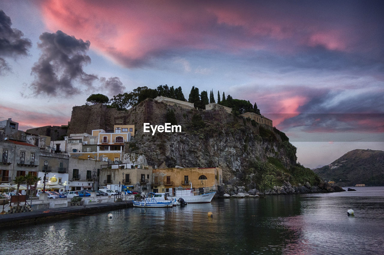 Low angle view of cliffed coastal town against pink sky