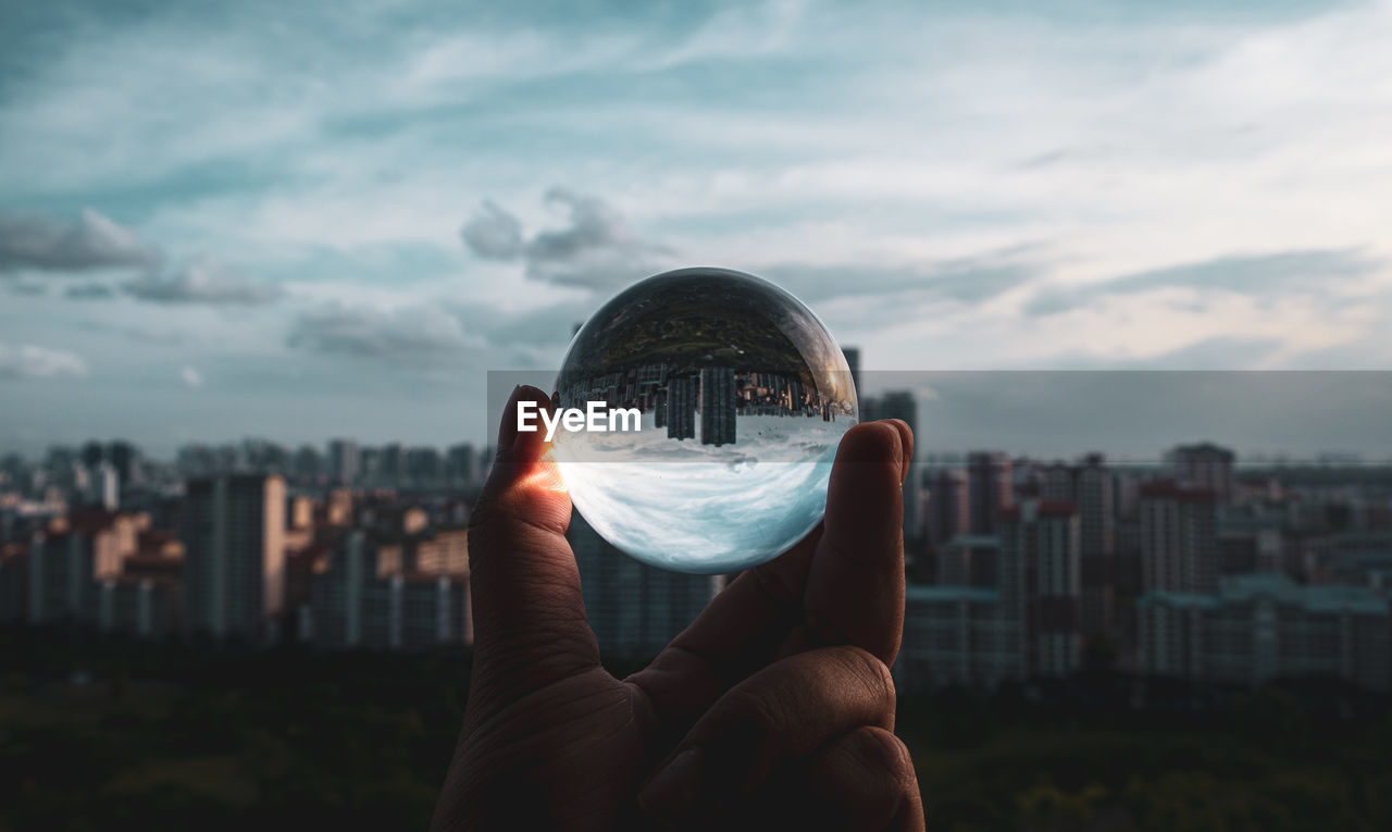 Person holding lens ball against cityscape
