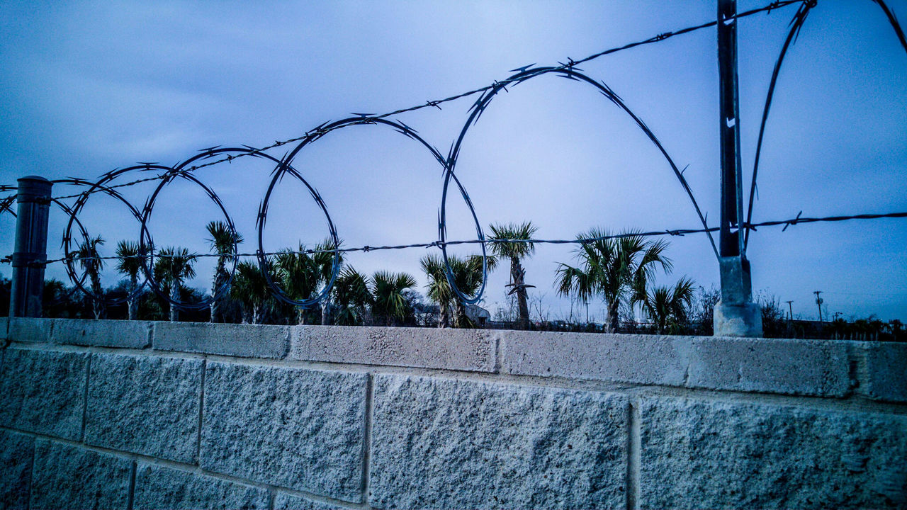 Barbed wires on wall at dusk