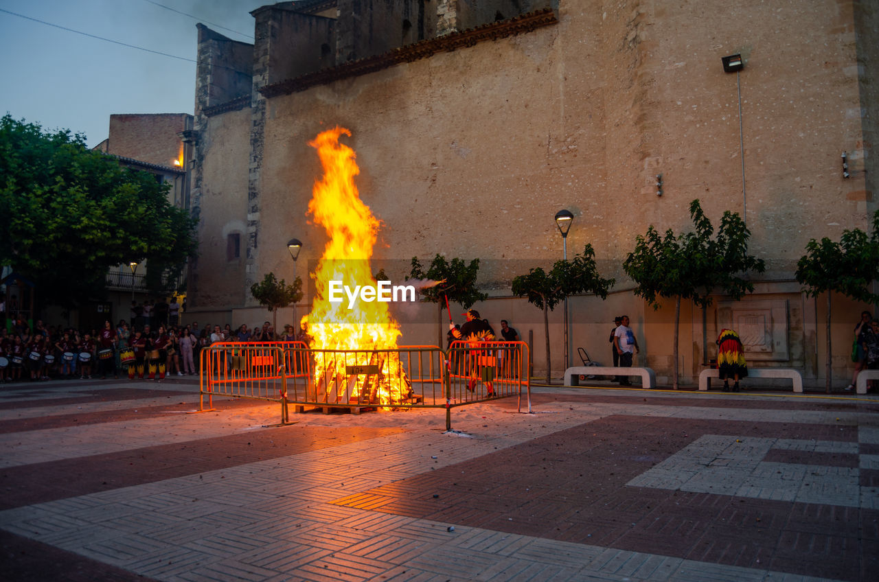 architecture, fire, burning, flame, building exterior, nature, heat, built structure, city, street, tree, night, plant, building, outdoors, group of people, travel destinations, tradition