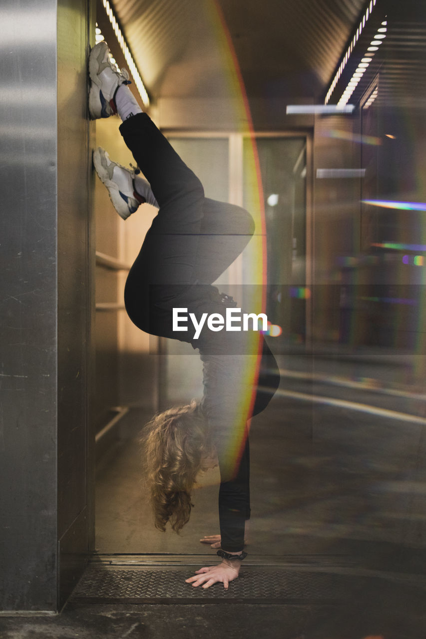 Side view of woman doing handstand at doorway