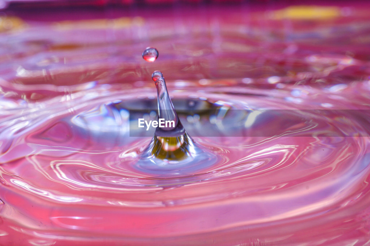 Close-up of drop falling in pink water