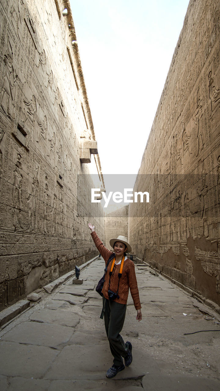 Full length of woman standing amidst wall