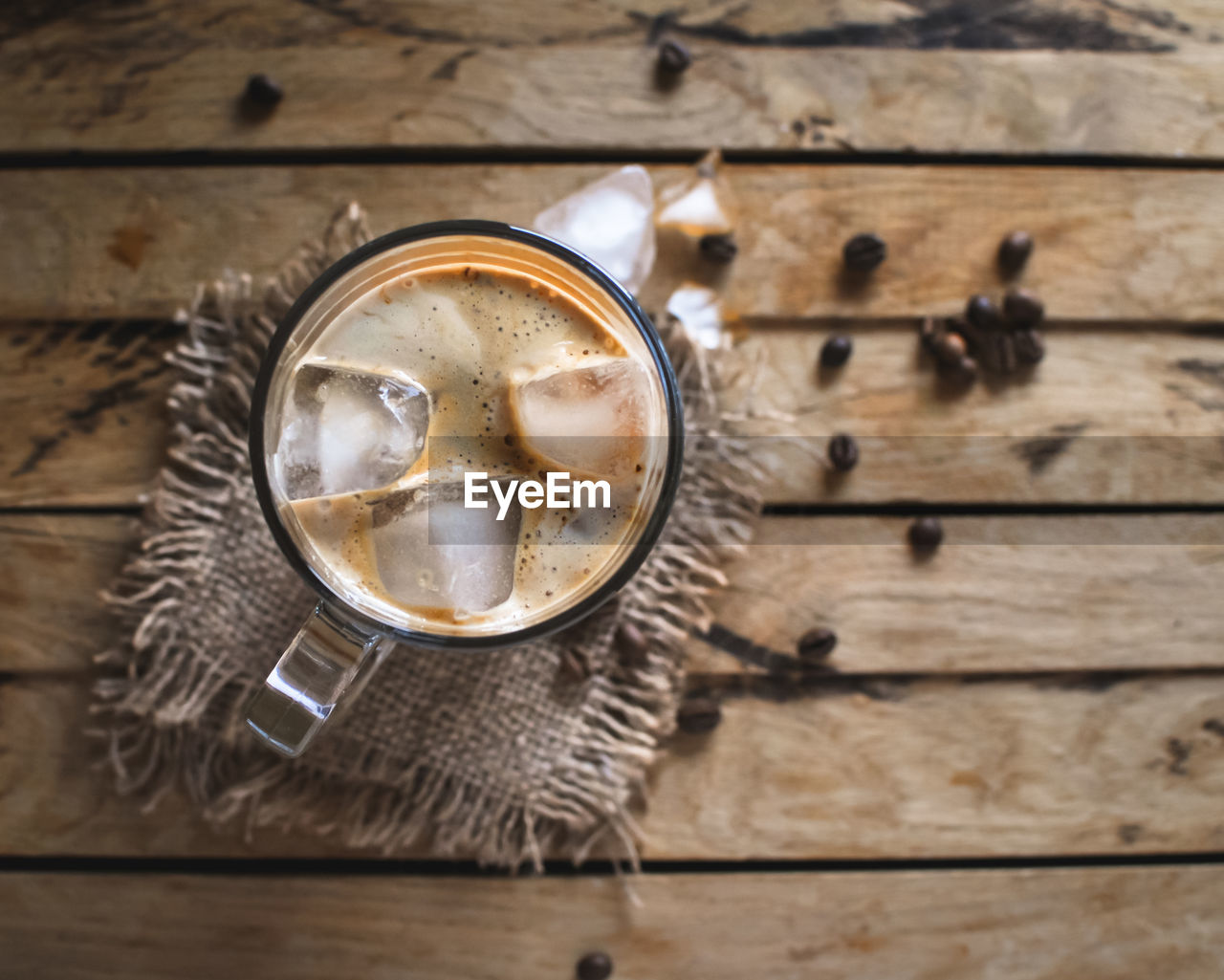 Close-up of ice coffee in a glass on wooden background, top view, copy space