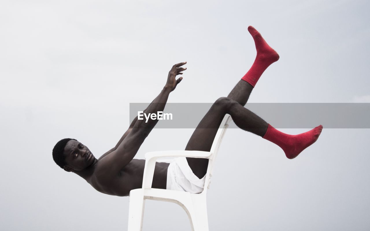 LOW ANGLE VIEW OF YOUNG WOMAN AGAINST SKY