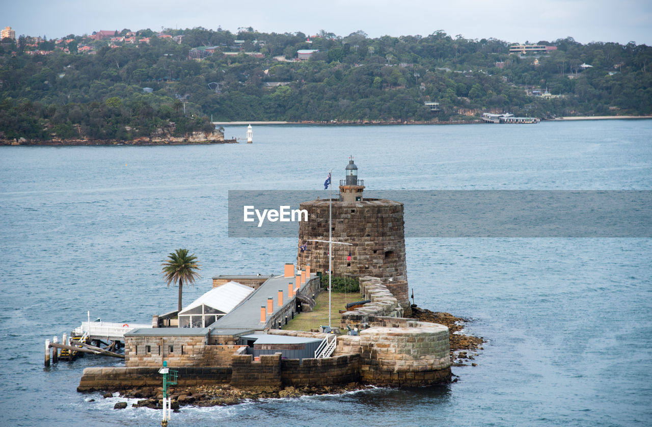 HIGH ANGLE VIEW OF BUILDINGS AND SEA AGAINST TREES