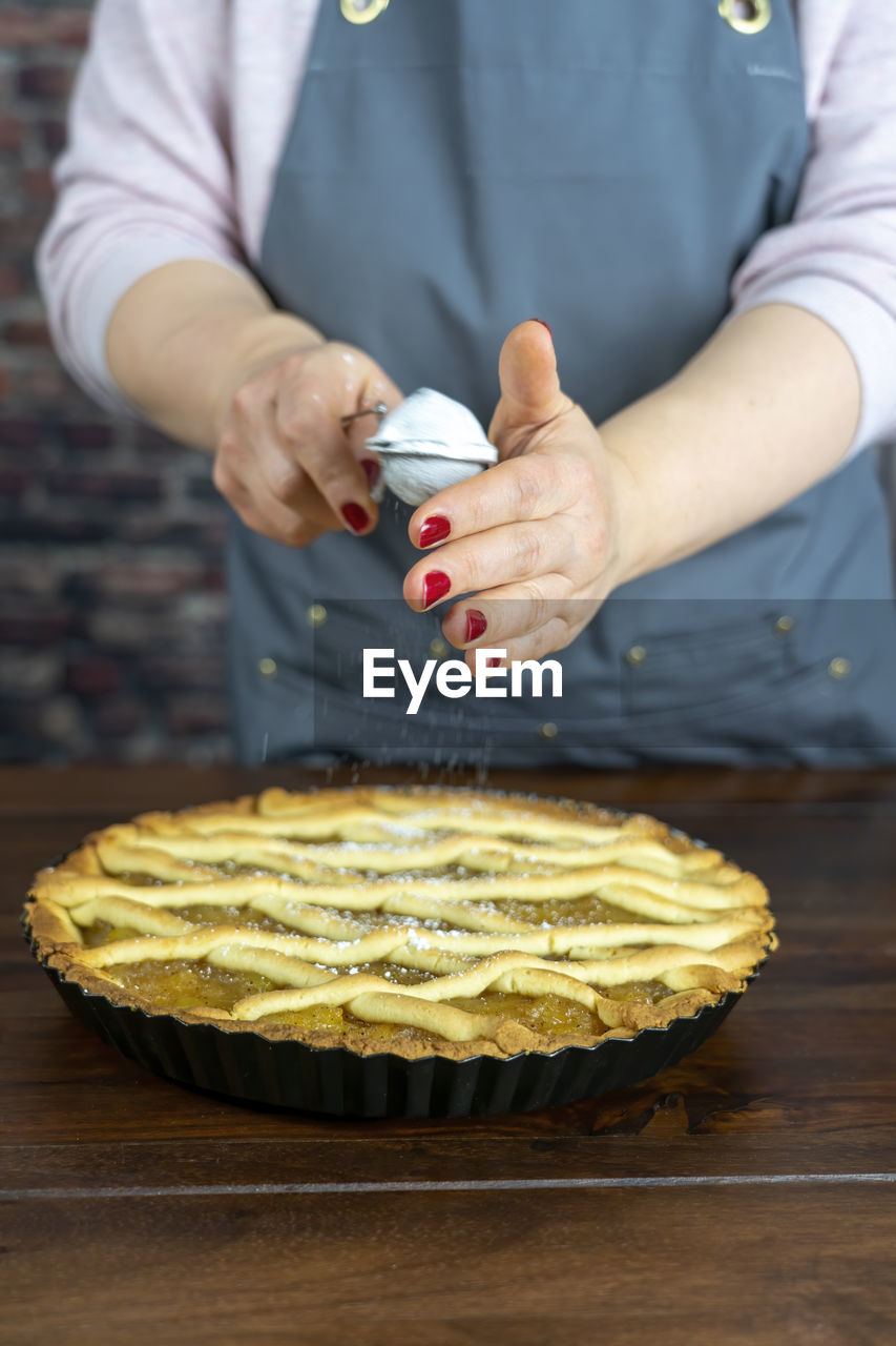 Women preparing delicious apple tart or pie large on wood table background.sprinkle powdered sugar