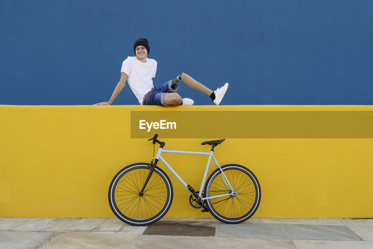 Young male with disability sitting near bike