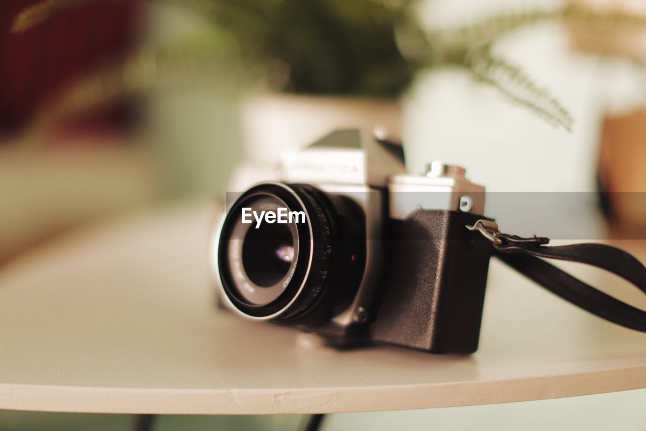 CLOSE-UP OF VINTAGE CAMERA ON TABLE AT HOME