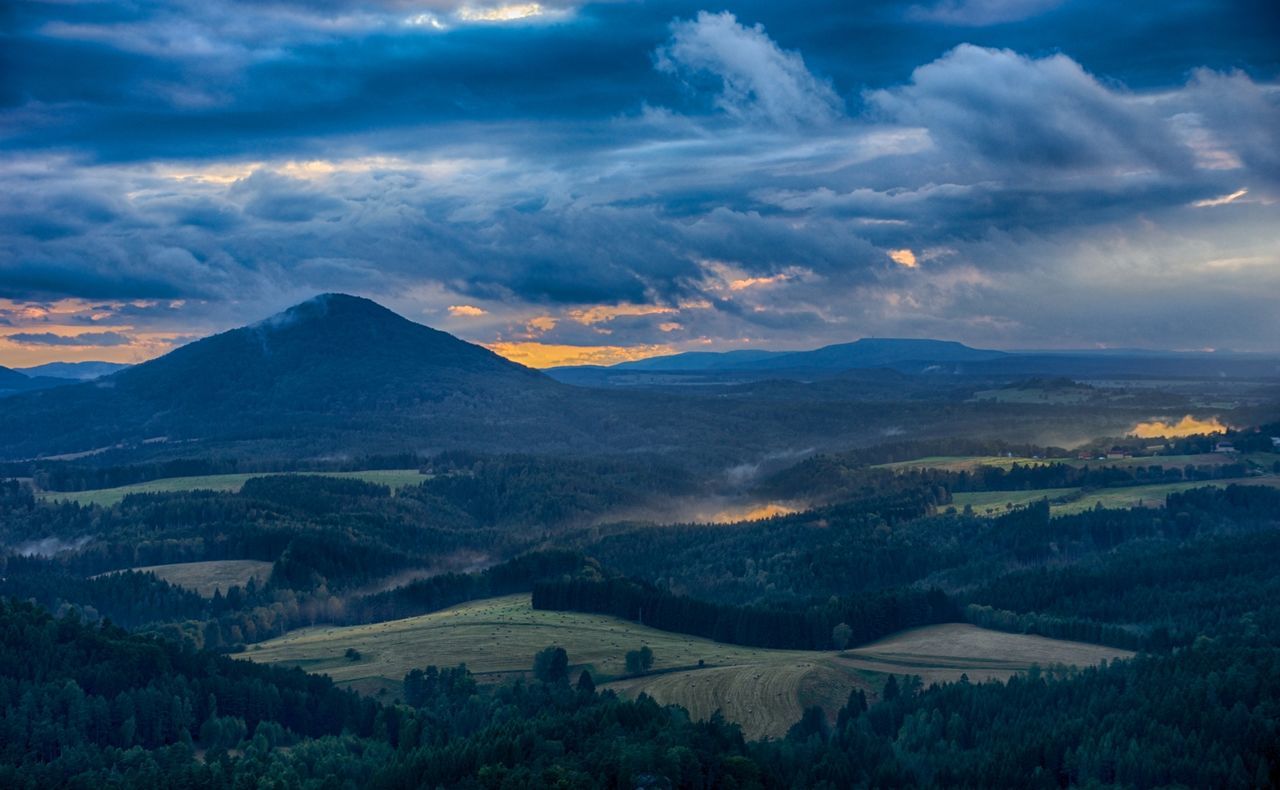 Scenic view of landscape against cloudy sky during sunset