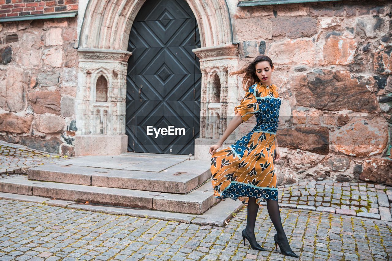 Young woman looking down while standing against building