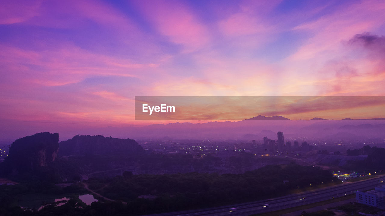 SCENIC VIEW OF BUILDINGS AGAINST CLOUDY SKY AT SUNSET