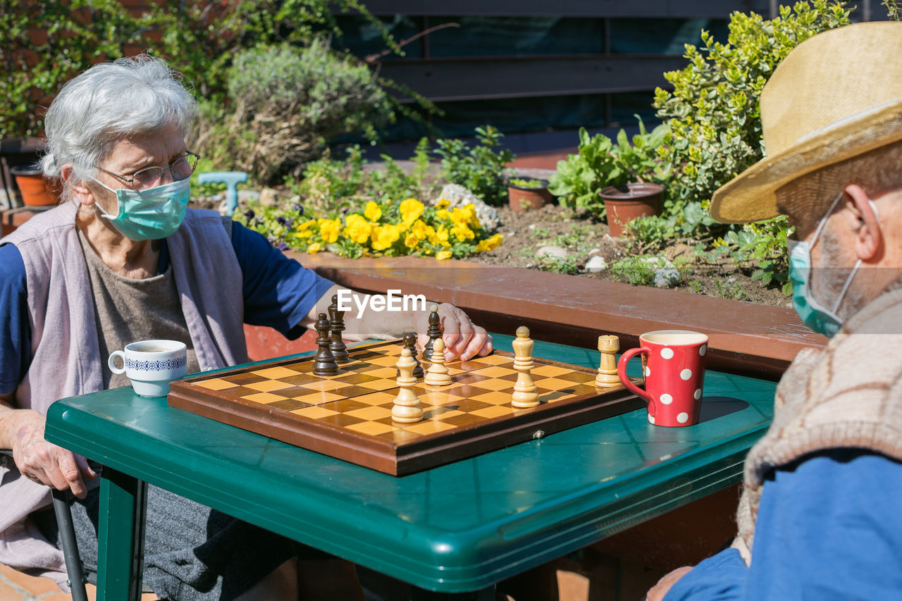 Senior couple playing chess on table while sitting outdoors