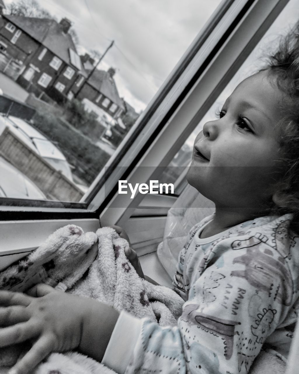 PORTRAIT OF CUTE GIRL LOOKING THROUGH WINDOW AGAINST SKY