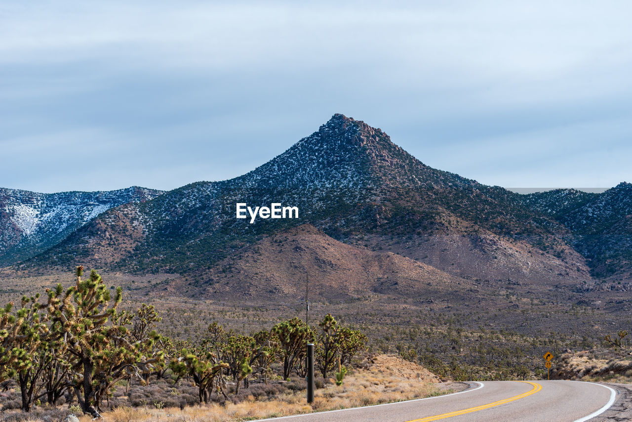 Road by mountains against sky