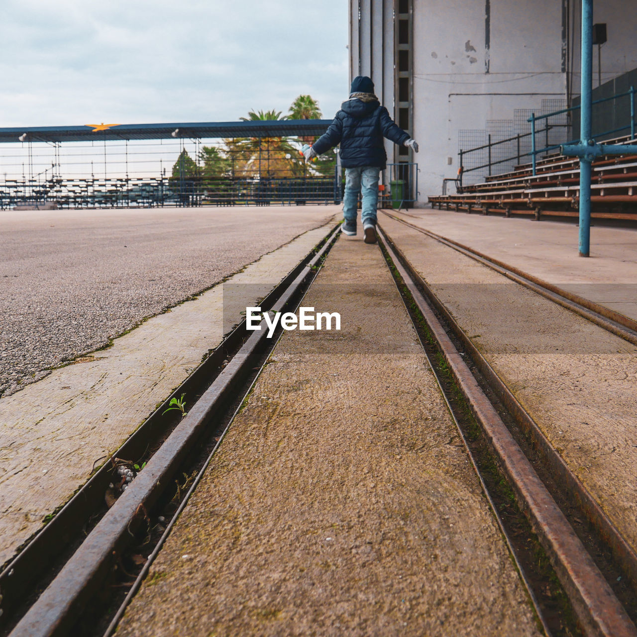 Rear view of boy walking on railroad track