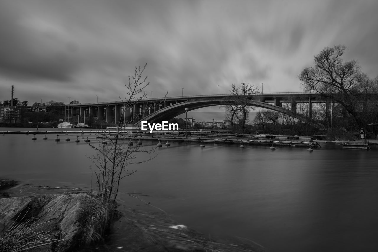 BRIDGE OVER RIVER WITH BUILDINGS IN BACKGROUND