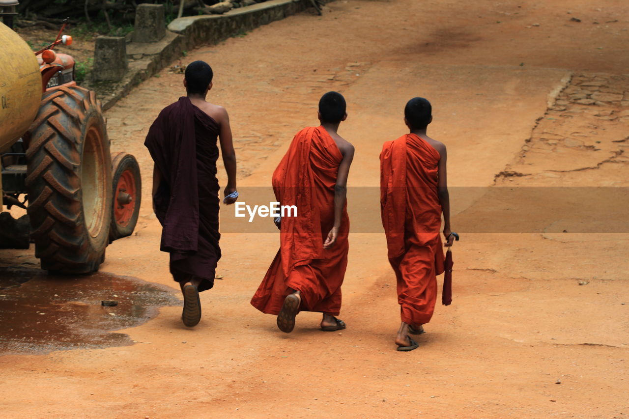 Rear view of monks walking on road