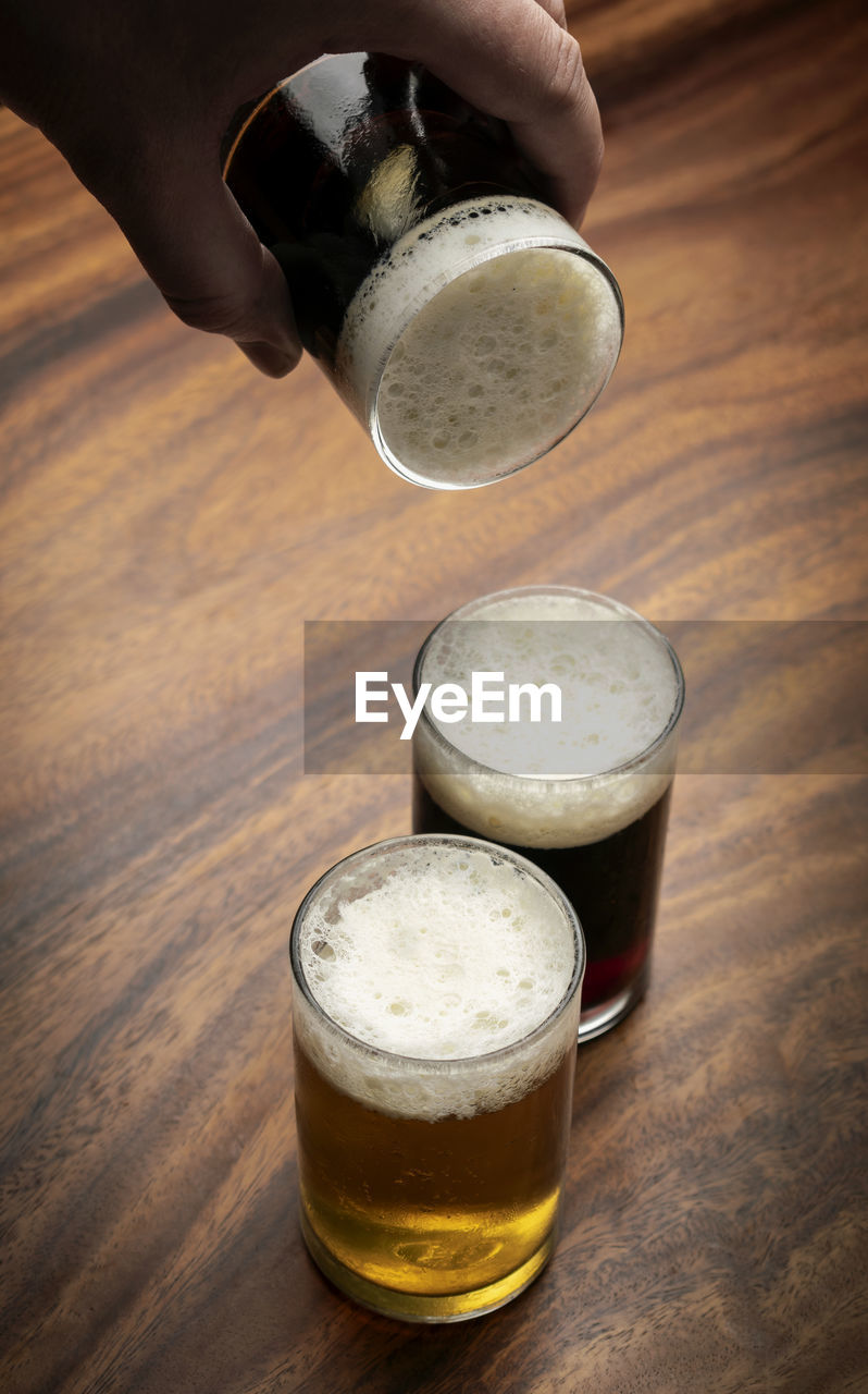 CLOSE-UP OF GLASS OF BEER ON WOODEN TABLE