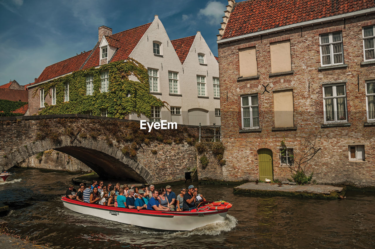 PEOPLE ON BOAT BY BUILDING