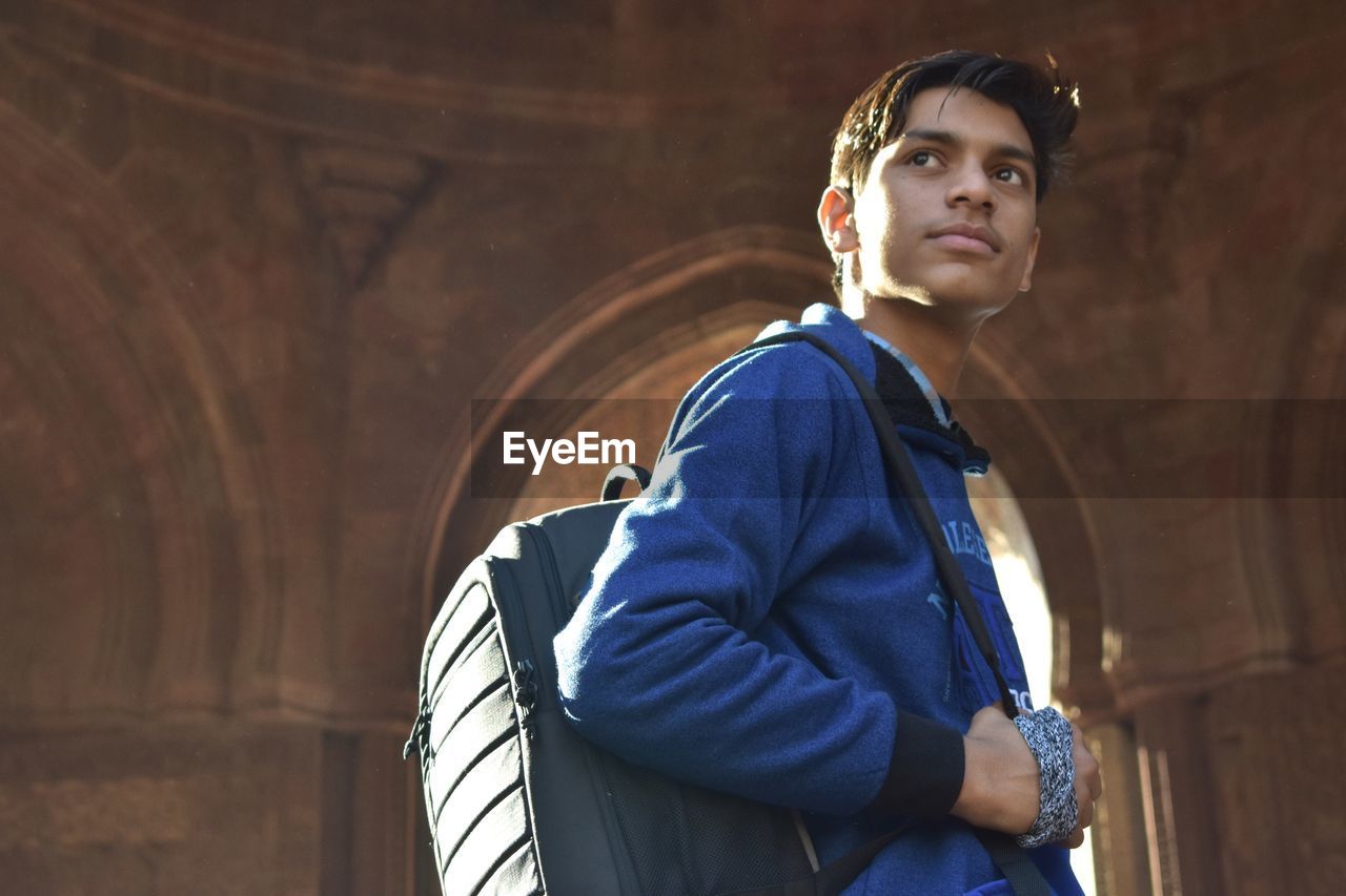 Young man looking away while standing in historic building
