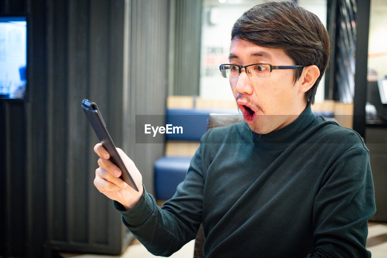 PORTRAIT OF YOUNG MAN LOOKING THROUGH CAMERA