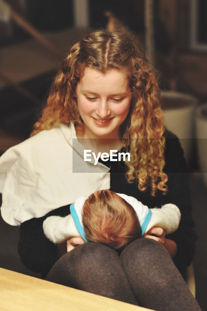 High angle view of mother holding baby while sitting at home