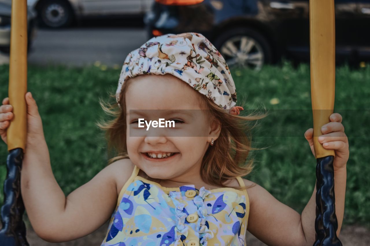 Portrait of cute girl smiling while sitting on swing in park