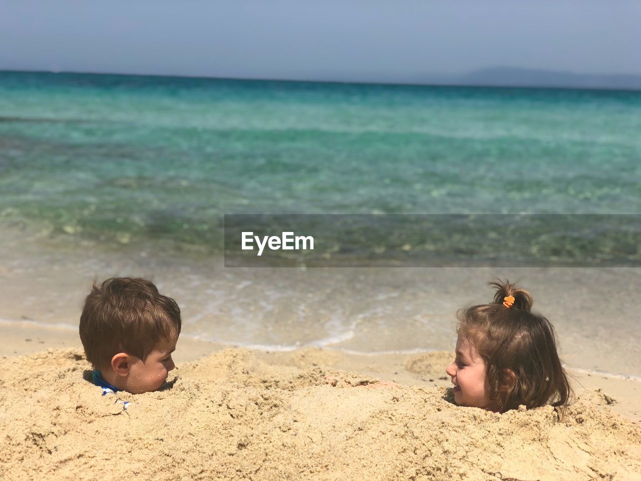 Siblings buried in sand at beach