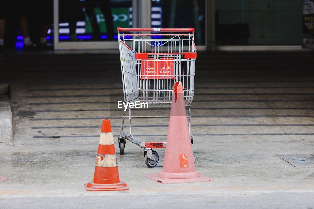 Empty shopping cart with traffic cone on road
