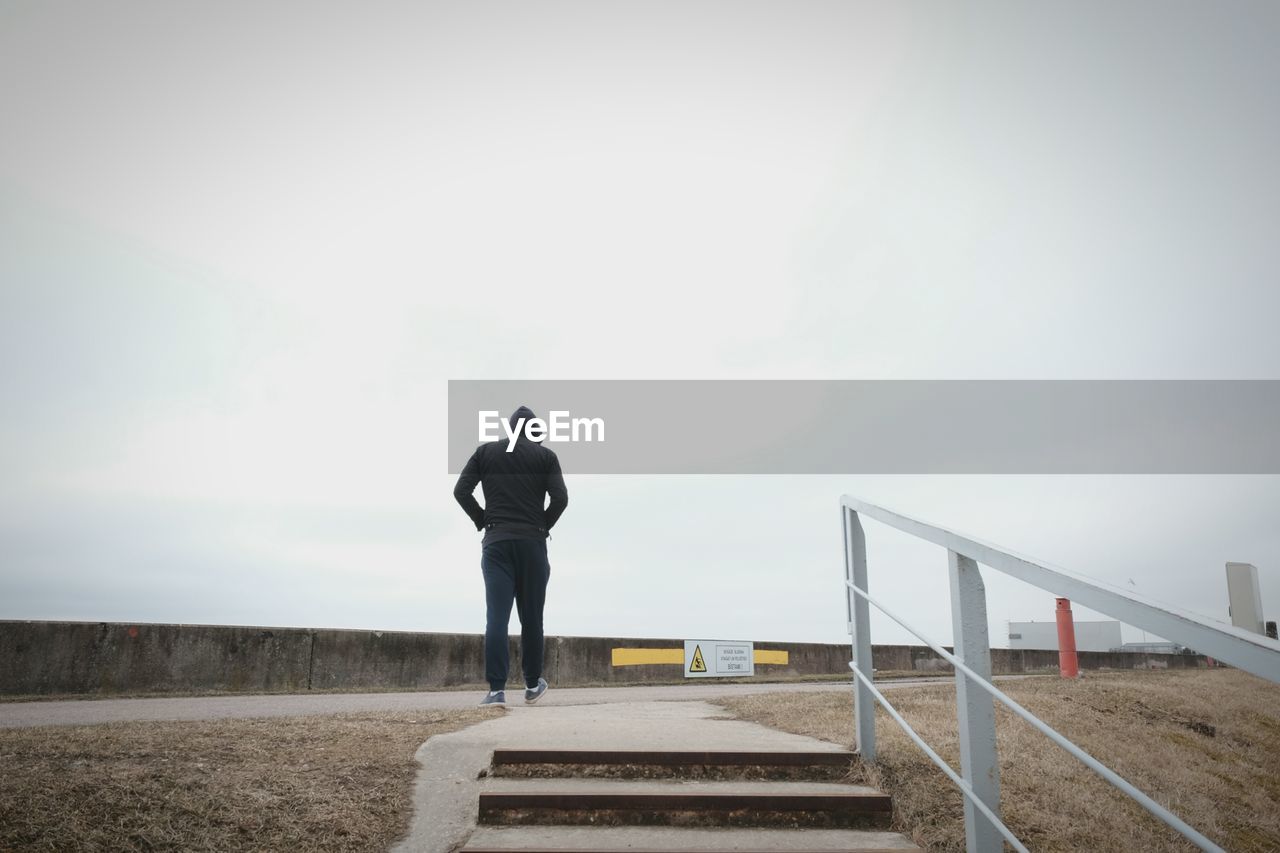 Rear view of man walking against clear sky