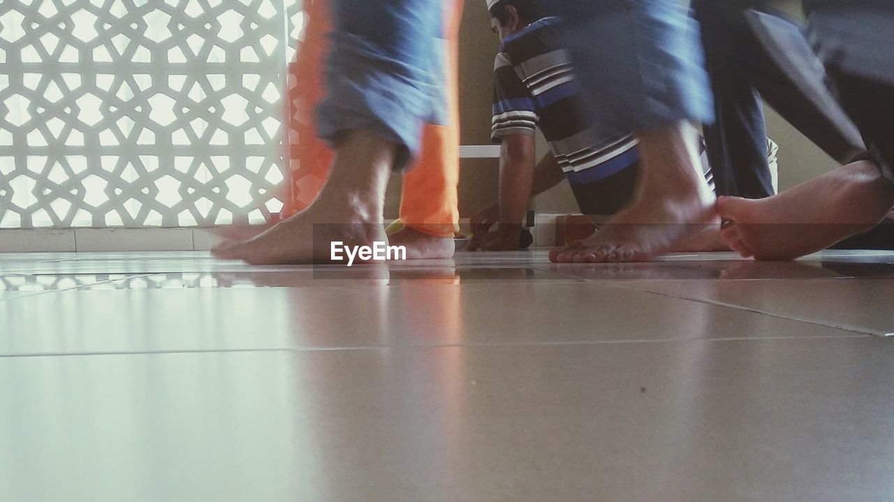 LOW SECTION OF WOMAN STANDING ON TILED FLOOR