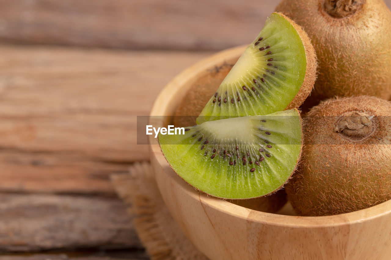 Close up kiwi in a wood bowl on the table.