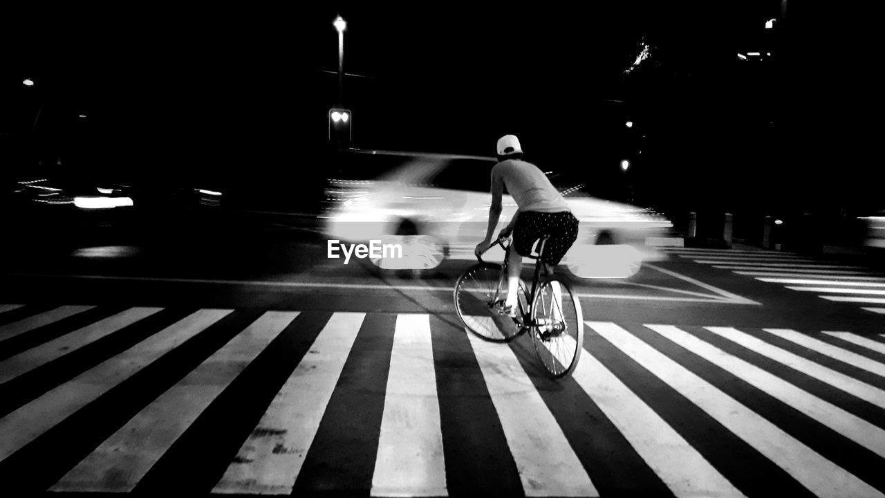 Man riding bicycle on road at night