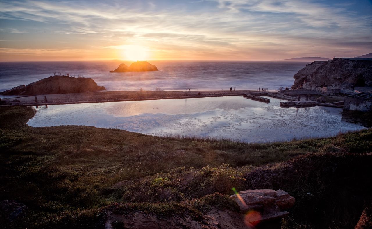 Scenic view of lake and sea against cloudy sky during sunset